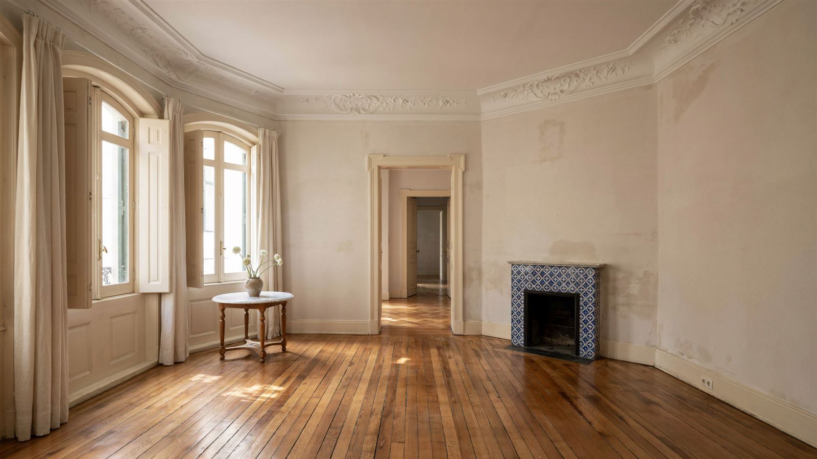Restored living room in an old Porto apartment with a polished wooden floor and tall windows